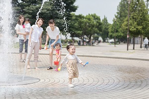 噴水で水遊びをする親子の写真