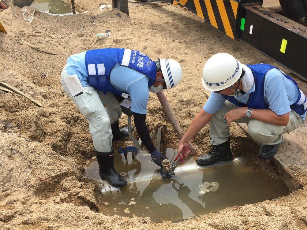 地面の中の水道管の復旧作業をしている作業員2名の写真