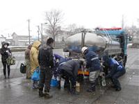 雪の中職員たちによる給水活動が行われている写真
