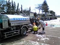 雪道に市民が長い行列を作って給水を待っている写真